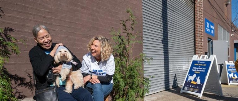 Two people laughing with small dog