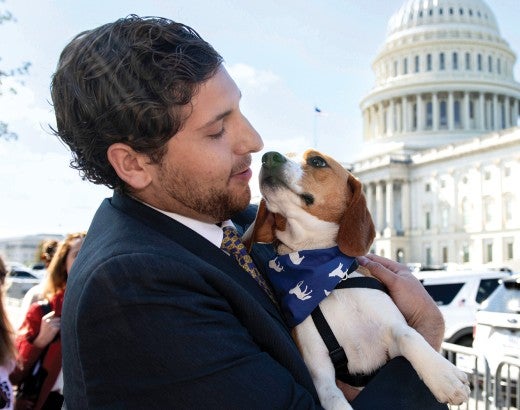 Man holding a beagle in front of the Capitol building in Washington, D.C.