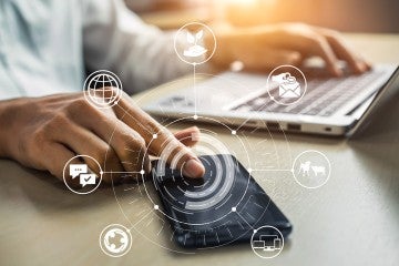Hand pressing on phone with a series of collaboration and communication icons