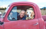 Jane Goodall in a red truck with a dog.