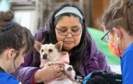 Brandi Markishtum holds pup Lola for a veterinary exam by veterinarian Colleen Cassidy, right, and veterinary assistant Sara Michelassi during the RAVS clinic serving the Quinault Nation.