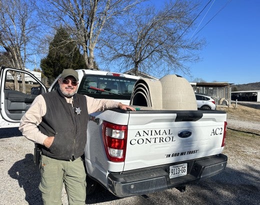 A man stands next to a truck filled with doghouses