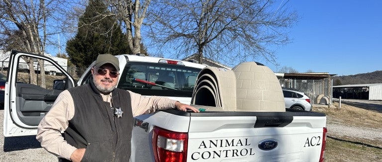 A man stands next to a truck filled with doghouses