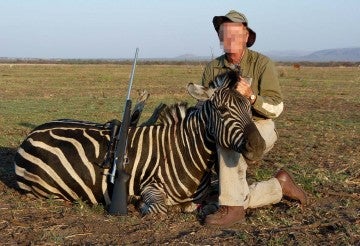 A hunter posing with a zebra he shot at a captive hunting ranch in South Africa.